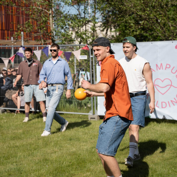 Et hold bestående af mænd står på høvdingeboldbanen med bolde i hænderne.
