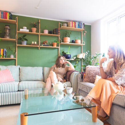 Natascha og Helena sidder i hver sin sofa i deres farverige lejlighed.