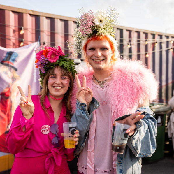 Konferencierne til Kontur kigger smilende ind i kameraet. De er iført pint høj, blomsterkranse og glitter.
