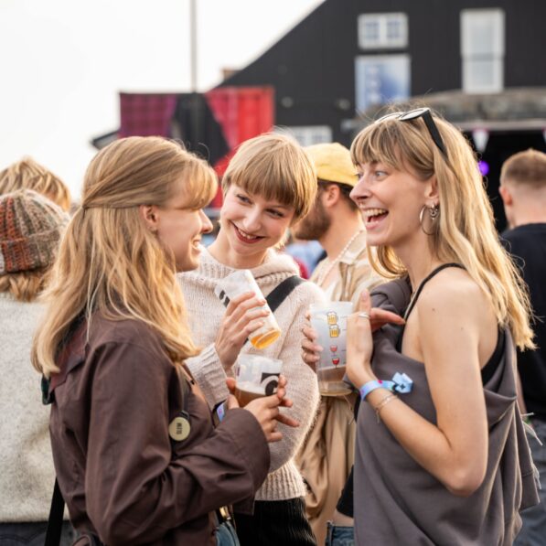 Tre kvinder står sammen på festivalpladsen og snakker passioneret.