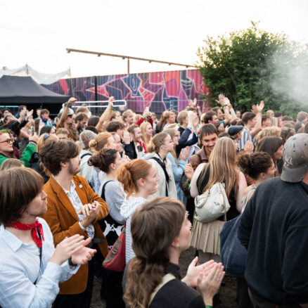 Et stort publikum af unge mennesker iført farverigt tøj står på festivalspladsen til Kontur 25 og kigger på mod scenen.