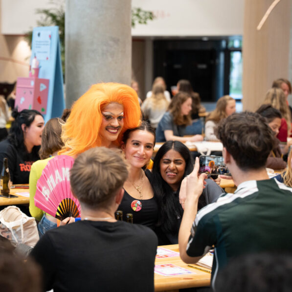 En mand tager et billede af drag queen og to kvinder blandt publikum