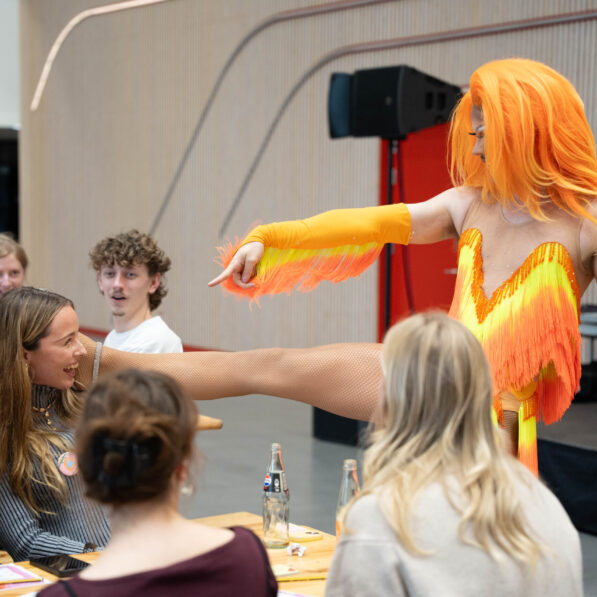 Dragqueen har benet oppe på tilskuer skulder