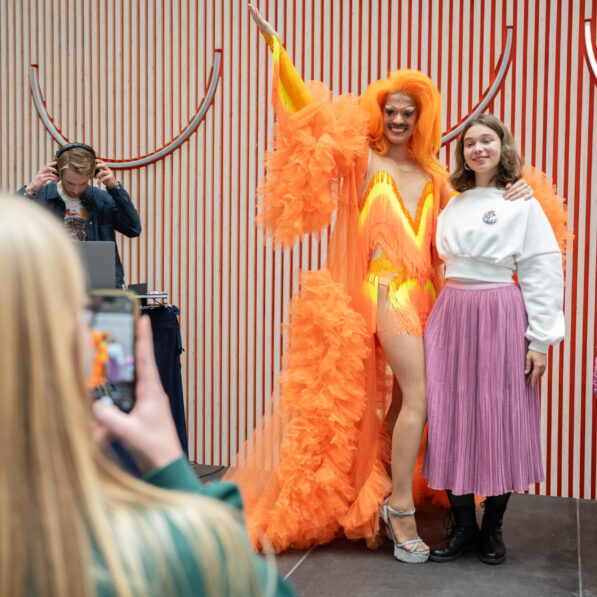 En kvinde tager et billede af en anden kvinde sammen med drag queen mizz privileze