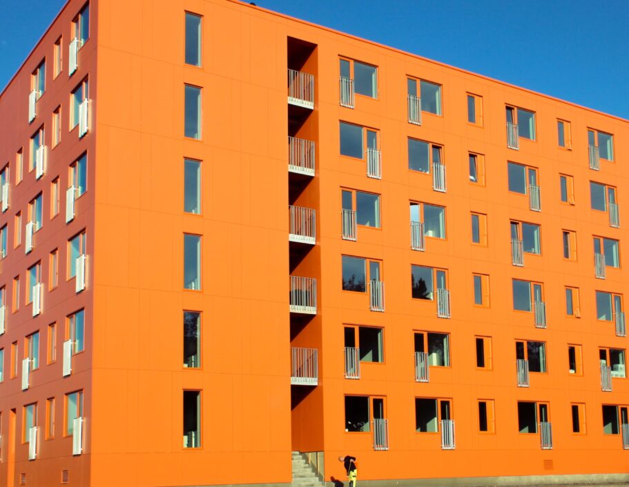 På billedet fremgår et stort, orange bygningskompleks med ungdomsboliger.