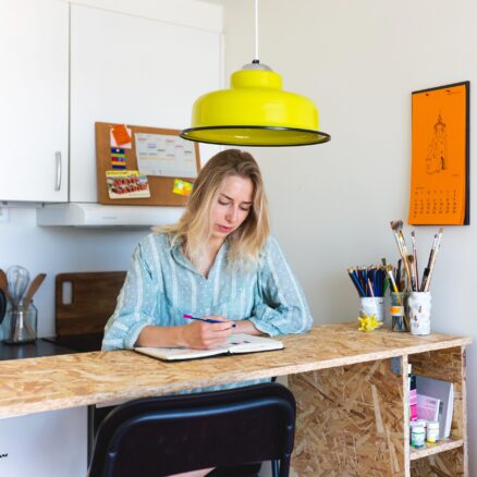 Julia sidder ved et skrivebord og tegner i en notesbog.