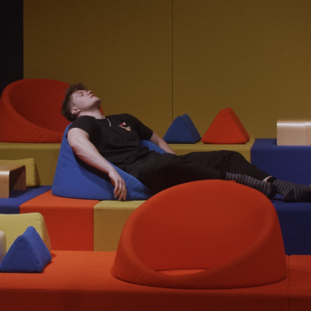 Tobias ligger afslappende i nogle farverige møbler ved kunstmuseum Trapholt.